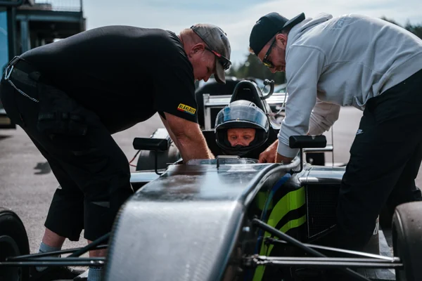 A driver being helped into a formula car